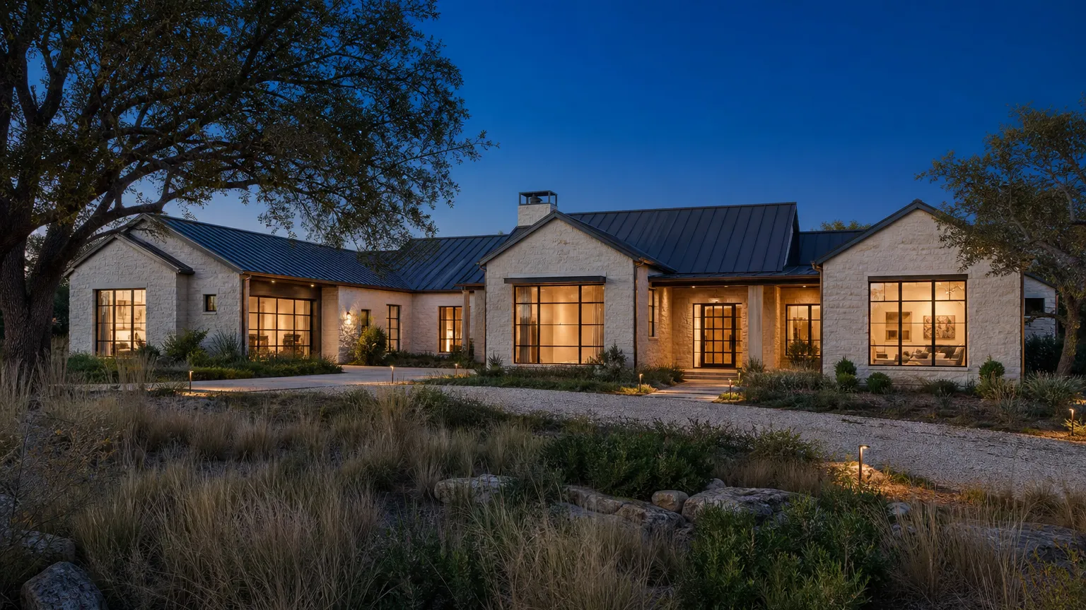 Completed modern Hill Country home at evening: limestone, black steel windows, standing-seam roof