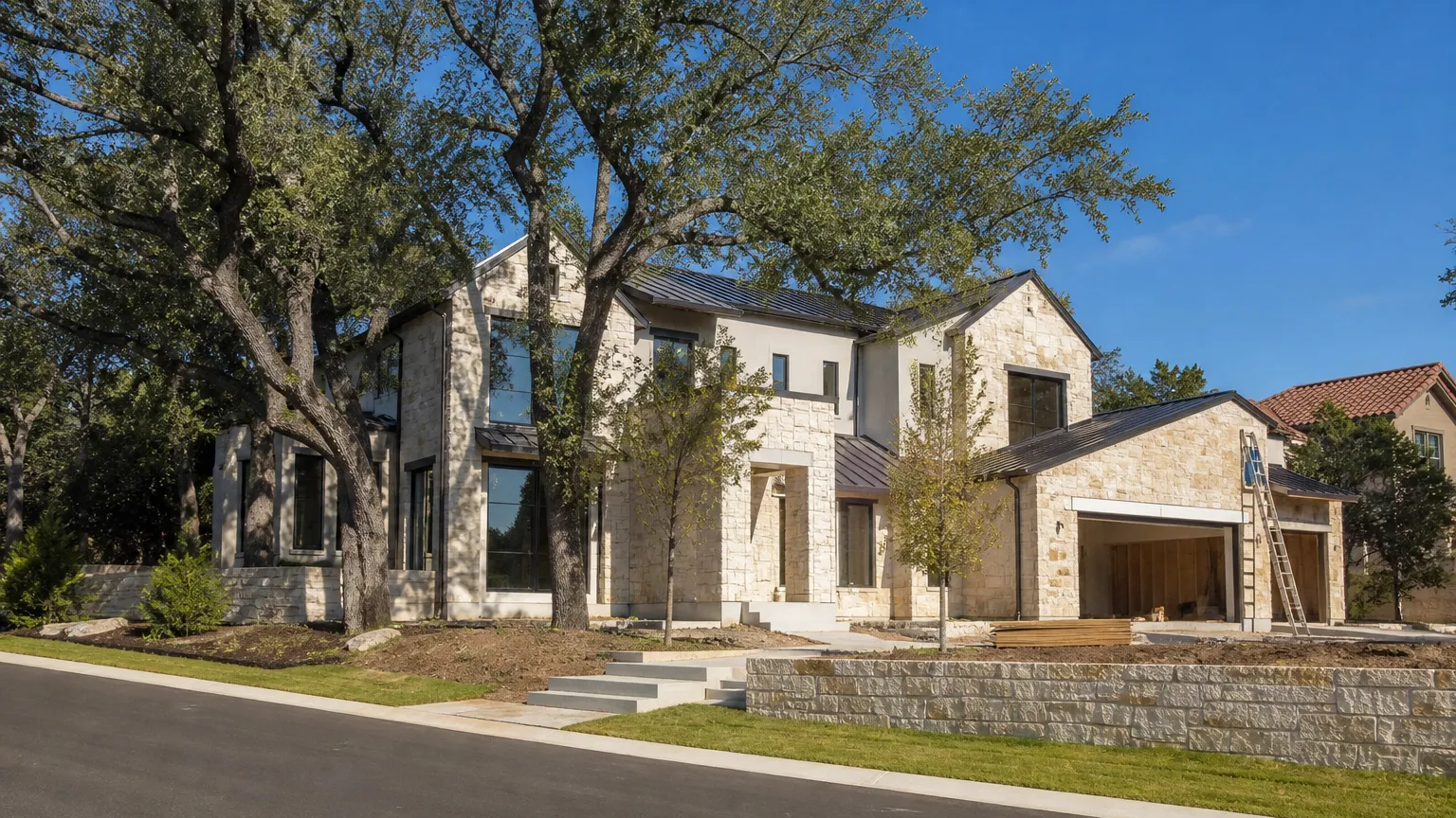 In Lakeway, Texas: contemporary limestone home under construction among preserved oaks